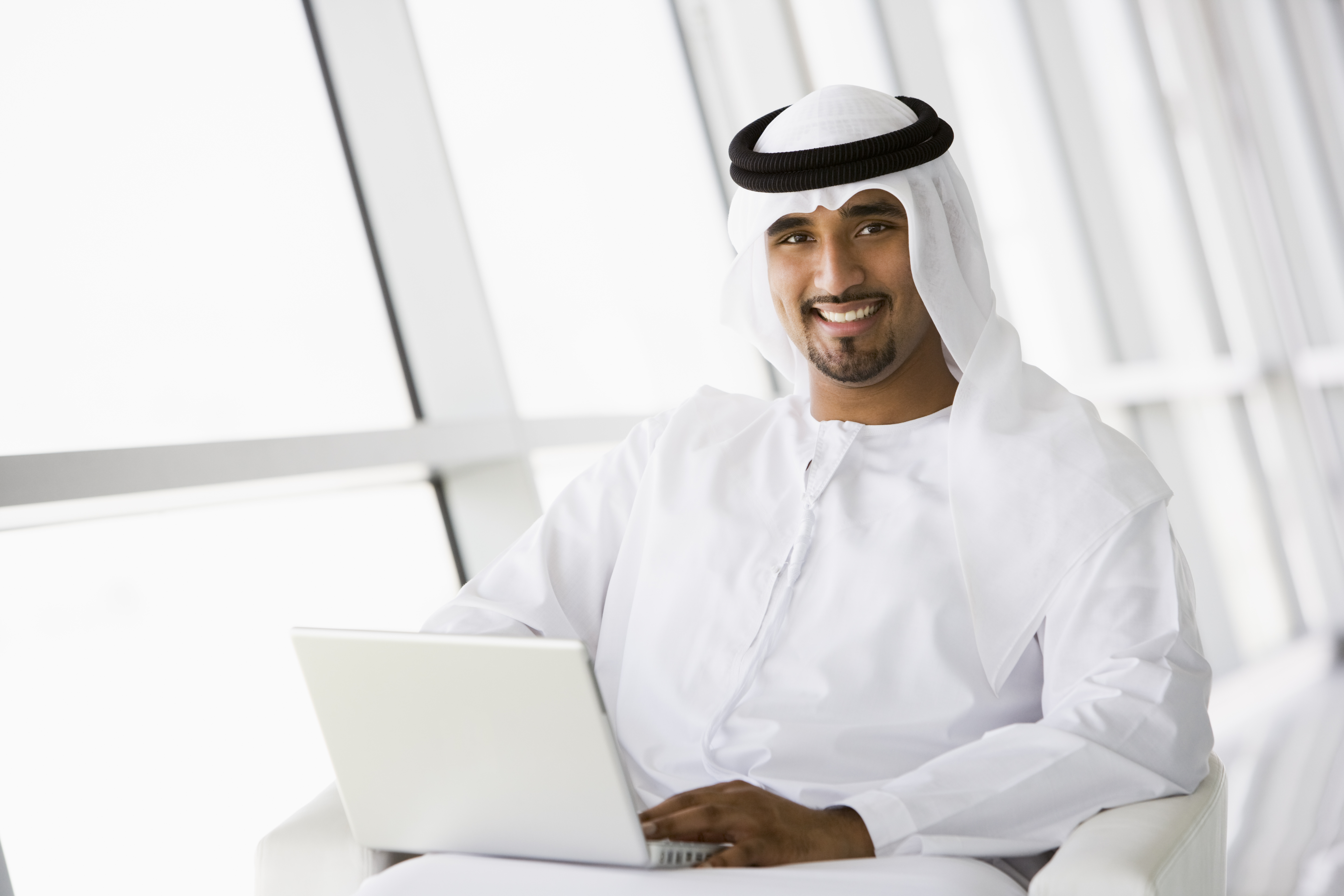 A digital professional in the Gulf working on a laptop in a light-filled office